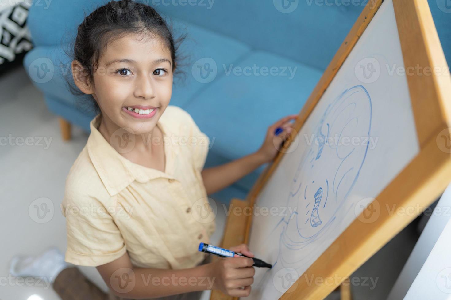 pequeno menina escrevendo em esvaziar quadro branco com uma marcador caneta foto