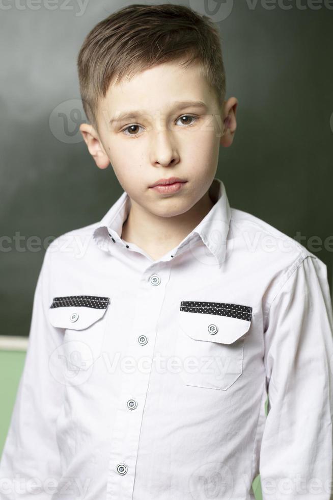 vertical retrato do uma estudante às a quadro-negro. a Garoto é dez anos velho dentro a aula. foto