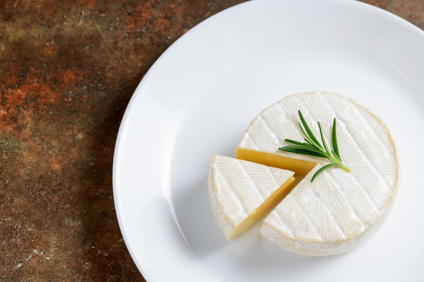 queijo Camembert queijo com alecrim em branco prato. foto