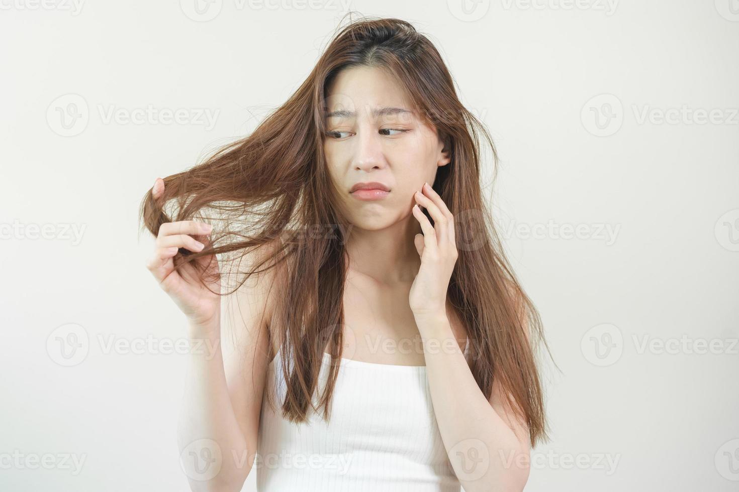 estragado cabelo, frustrado ásia jovem mulher, menina mão dentro segurando divisão termina, bagunçado não escovado seco cabelo com face choque, grandes desgrenhado cabelo, saúde Cuidado do beleza. retrato isolado em fundo. foto