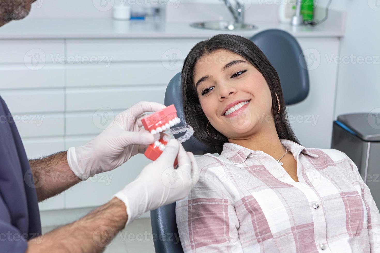 colheita dentista mostrando alinhadores para étnico fêmea cliente foto