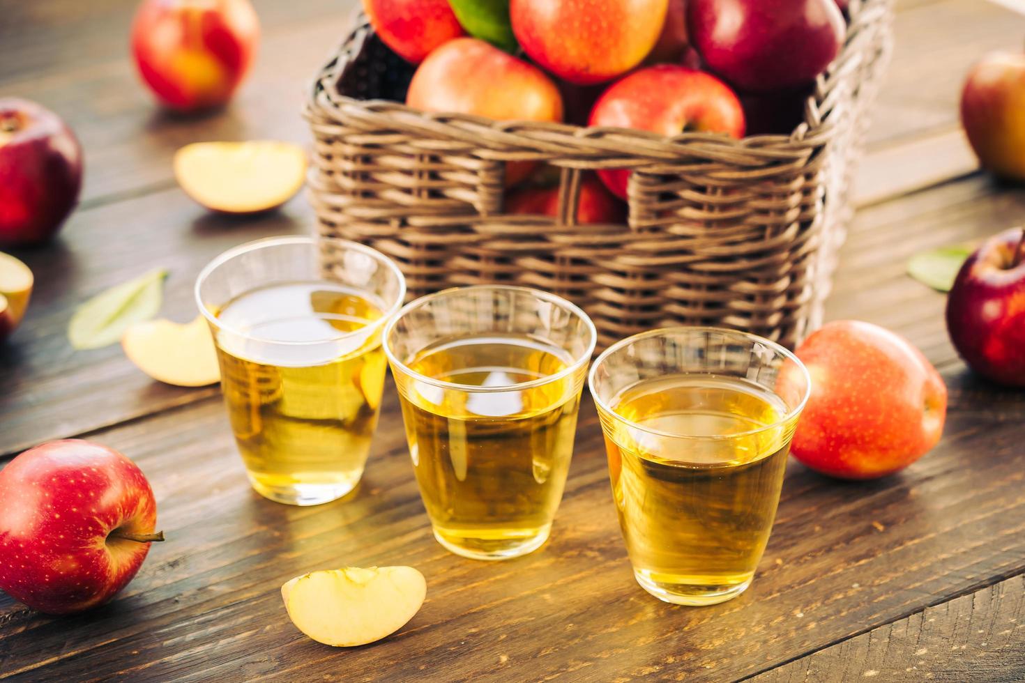 suco de maçã em copos e maçãs na cesta foto