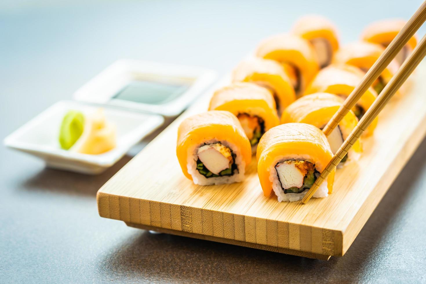 Rolinhos de sushi de salmão no prato de madeira foto