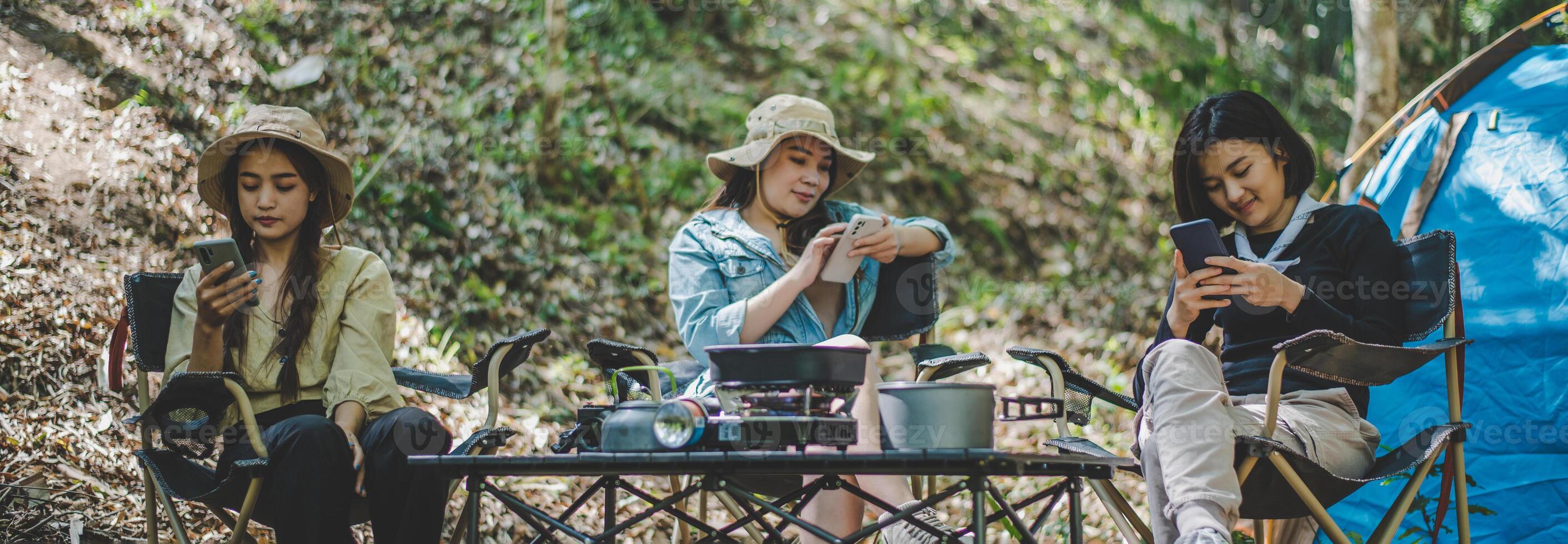 grupo de amigas com smartphone enquanto acampava no parque foto