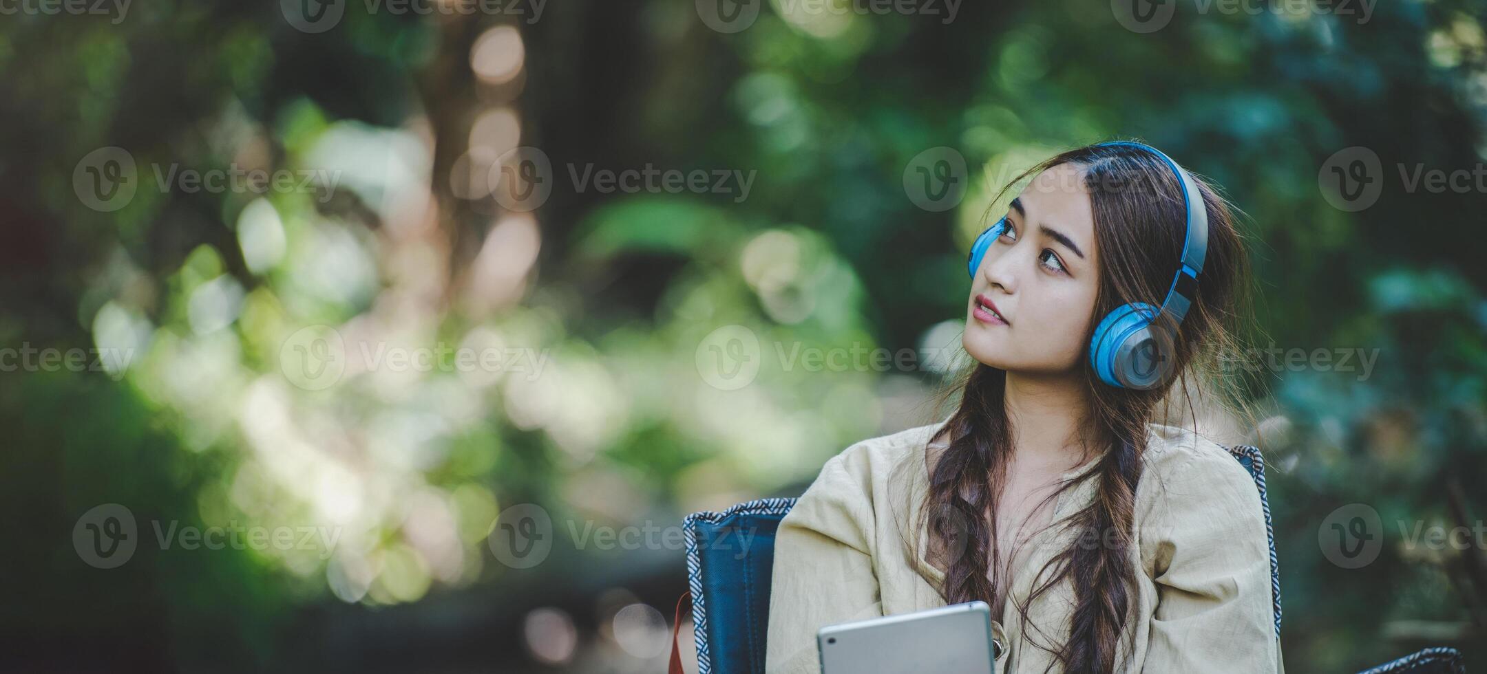 jovem mulher asiática sentada na cadeira ouvindo música do fone de ouvido foto