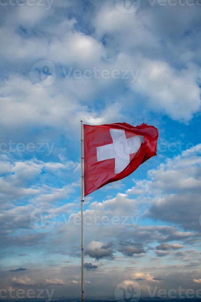 suíço bandeira sopro dentro a vento, a fundo é uma nublado céu foto