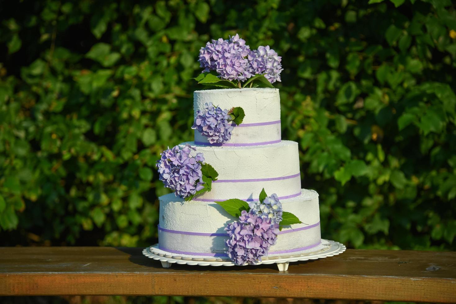 uma foto de um bolo de casamento com hortênsias de flores violetas
