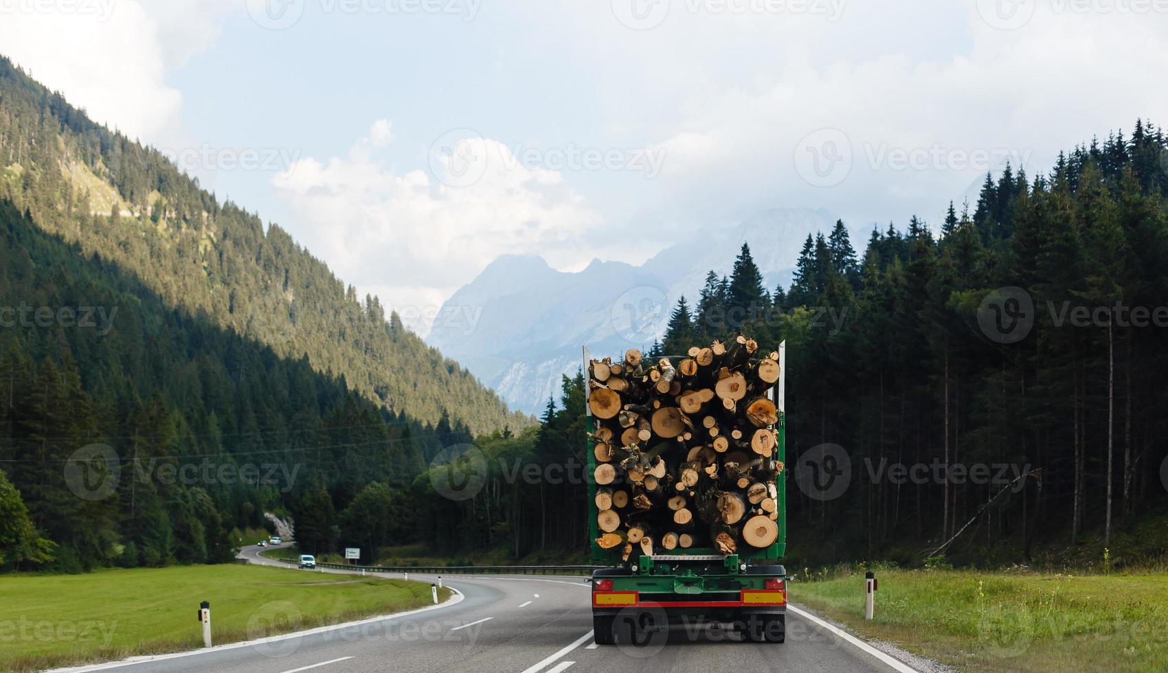 uma ampla caminhão transportando madeira em uma montanha estrada foto