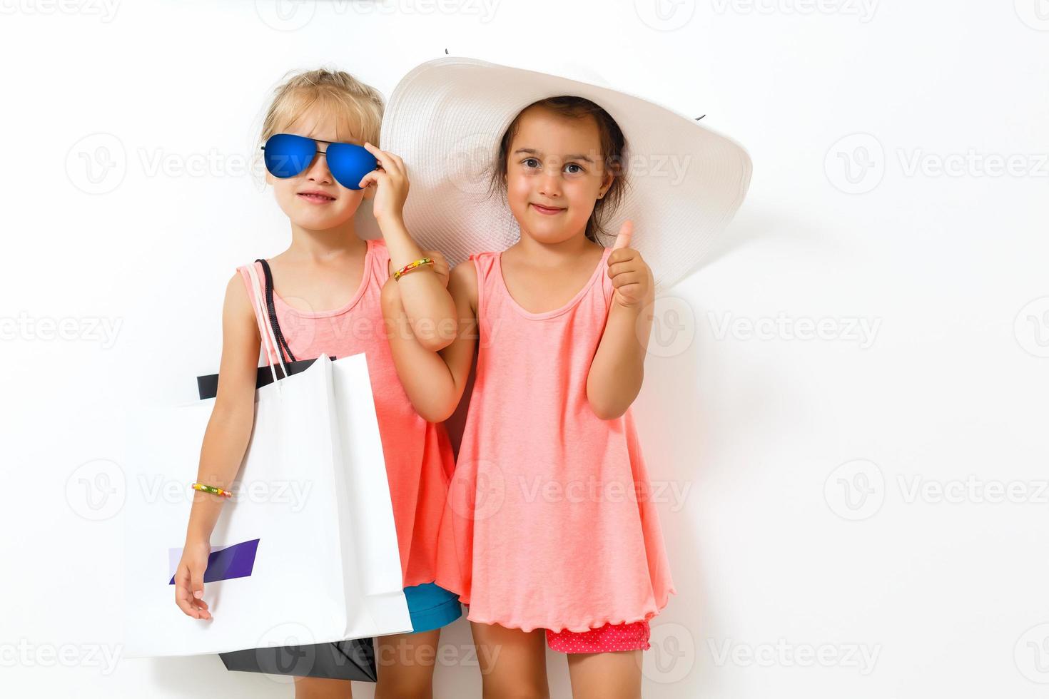 dois fofa meninas com compras bolsas em branco fundo foto