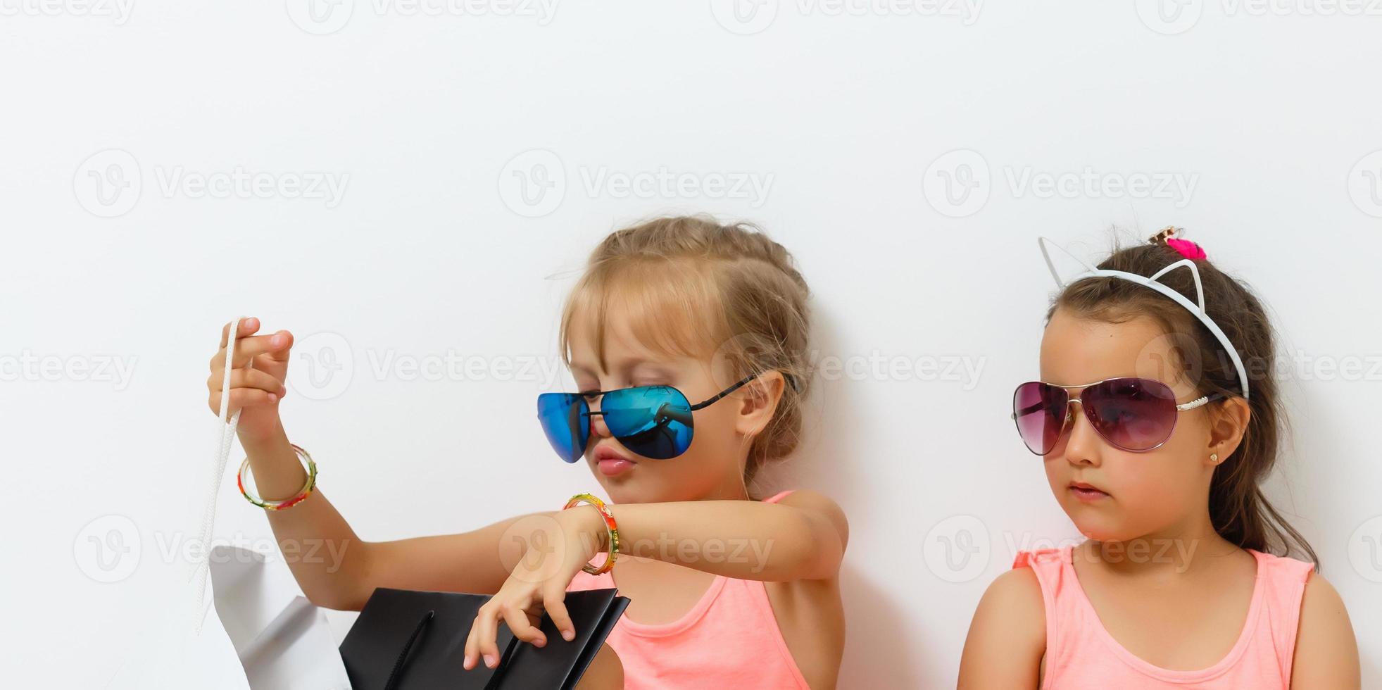 dois fofa meninas com compras bolsas em branco fundo foto