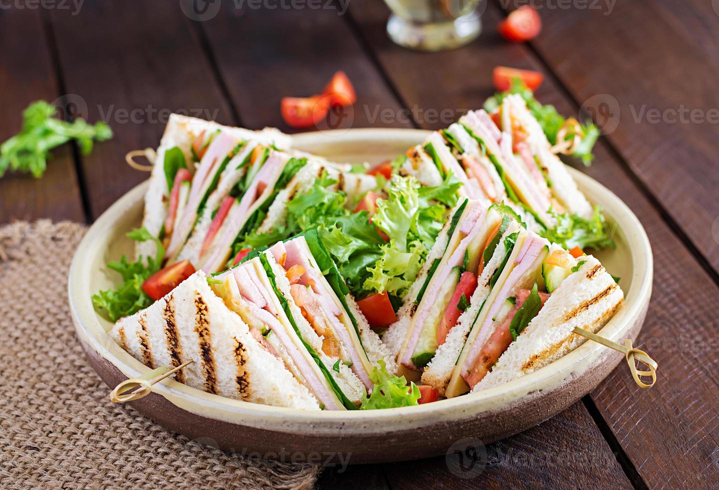 clube sanduíche com presunto, tomate, pepino, queijo, e Rúcula em de madeira fundo. foto