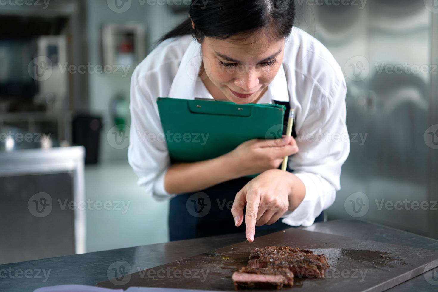 retrato do aluna cozinhando Aprendiz levar notas em cada degrau Como a chefe de cozinha cozinheiros dentro a culinária da academia cozinha. foto