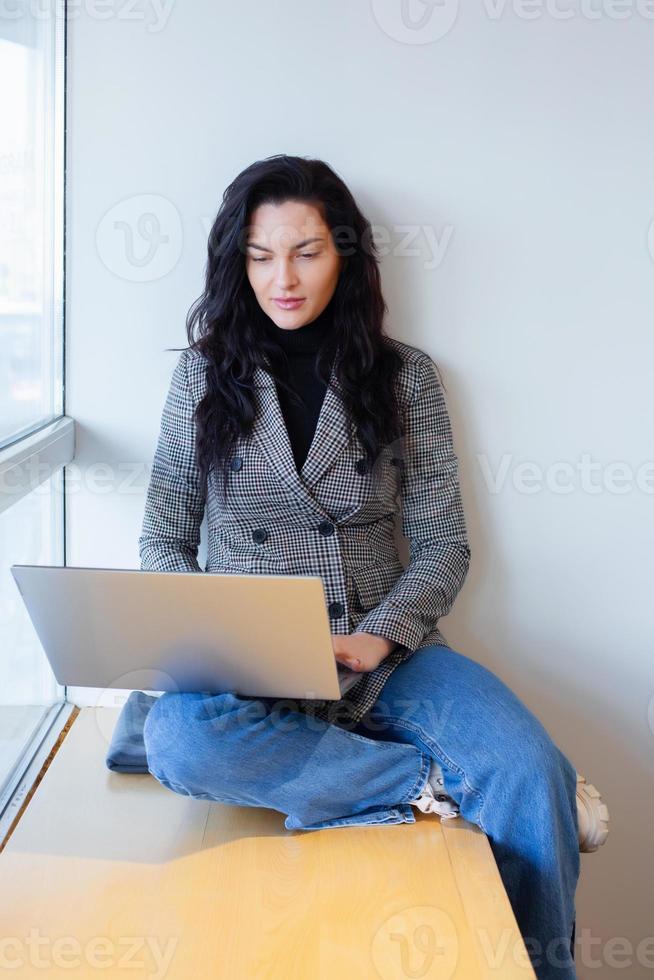 lindo empresária trabalhando em uma computador portátil. fêmea trabalhador autonomo conectando para Internet através da computador. blogueiro ou jornalista escrevendo Novo artigo. foto