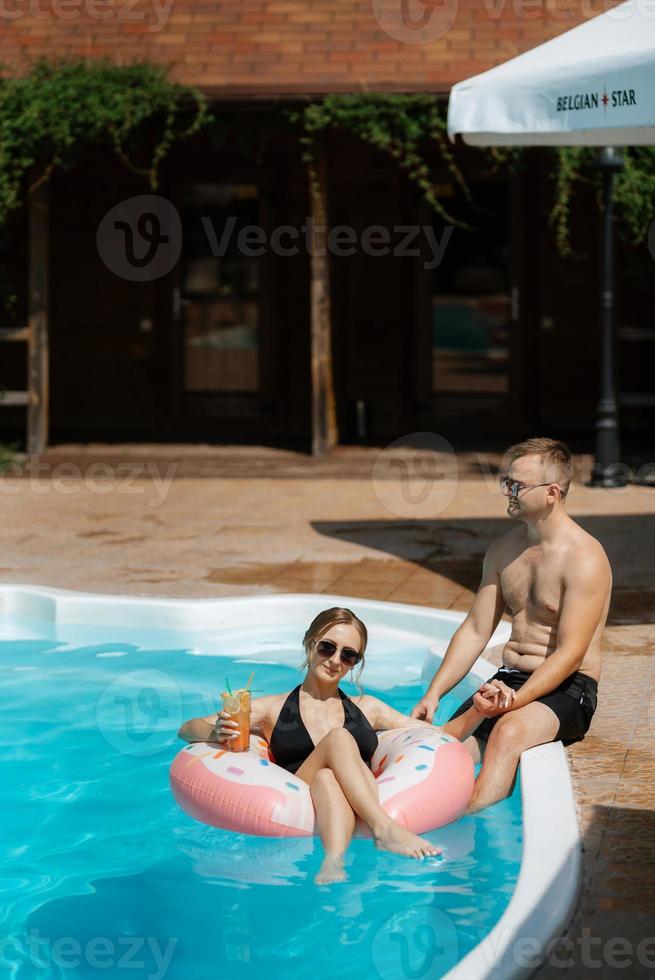 cara e uma menina dentro tomando banho ternos estão relaxante, perto a azul piscina foto