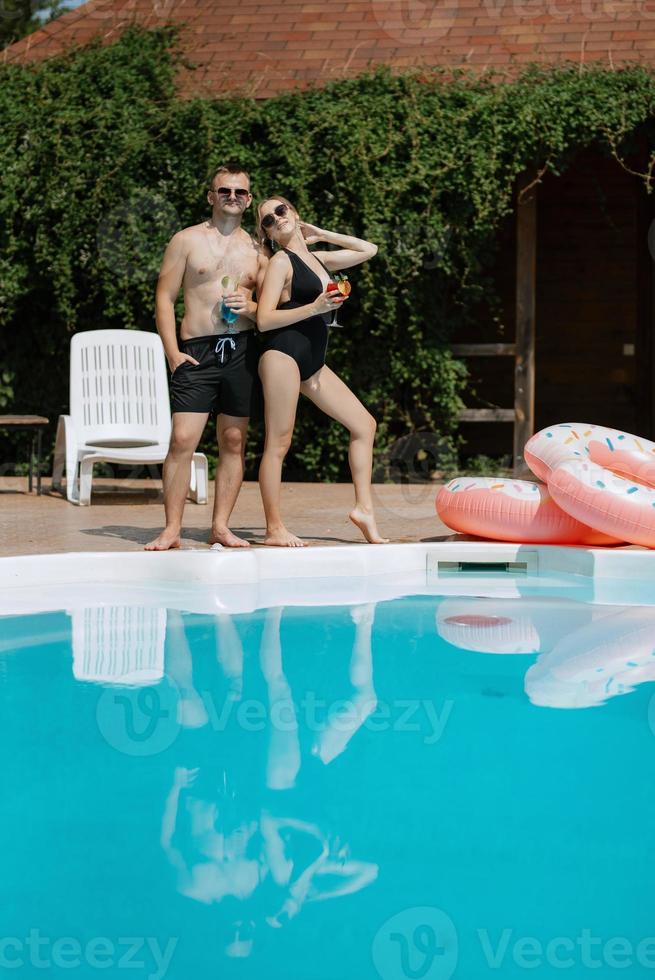 cara e uma menina dentro tomando banho ternos estão relaxante, perto a azul piscina foto