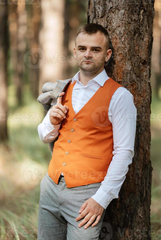 retrato do a noivo dentro uma cinzento terno e a laranja colete foto