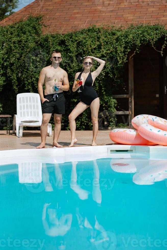 cara e uma menina dentro tomando banho ternos estão relaxante, perto a azul piscina foto