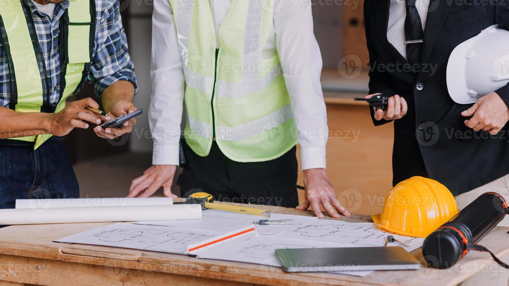 engenheiro de canteiro de obras de dois homens de negócios. objetos de engenharia no local de trabalho com parceiros interagindo em segundo plano foto