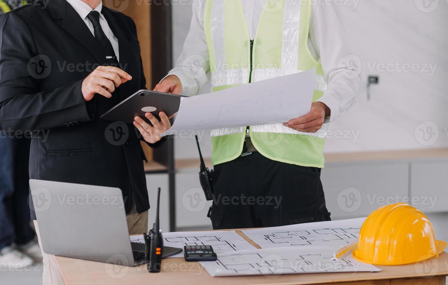 engenheiro de canteiro de obras de dois homens de negócios. objetos de engenharia no local de trabalho com parceiros interagindo em segundo plano foto