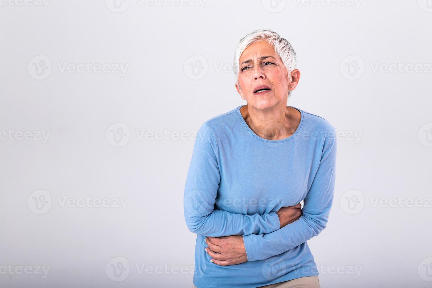 mulher madura insalubre segurando a barriga, sentindo desconforto, conceito de problema de saúde, mulher mais velha infeliz sentada na cama, sofrendo de dor de estômago, intoxicação alimentar, gastrite, dor abdominal, clímax foto