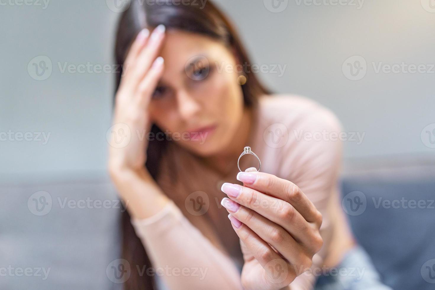 jovem mulher segurando Casamento noivado anel dentro mãos, acionado menina duvida sobre casamento proposta, abandonado esposa depressivo depois de obtendo divorciado, Socorro para superar quebra acima, iniciando Novo vida foto