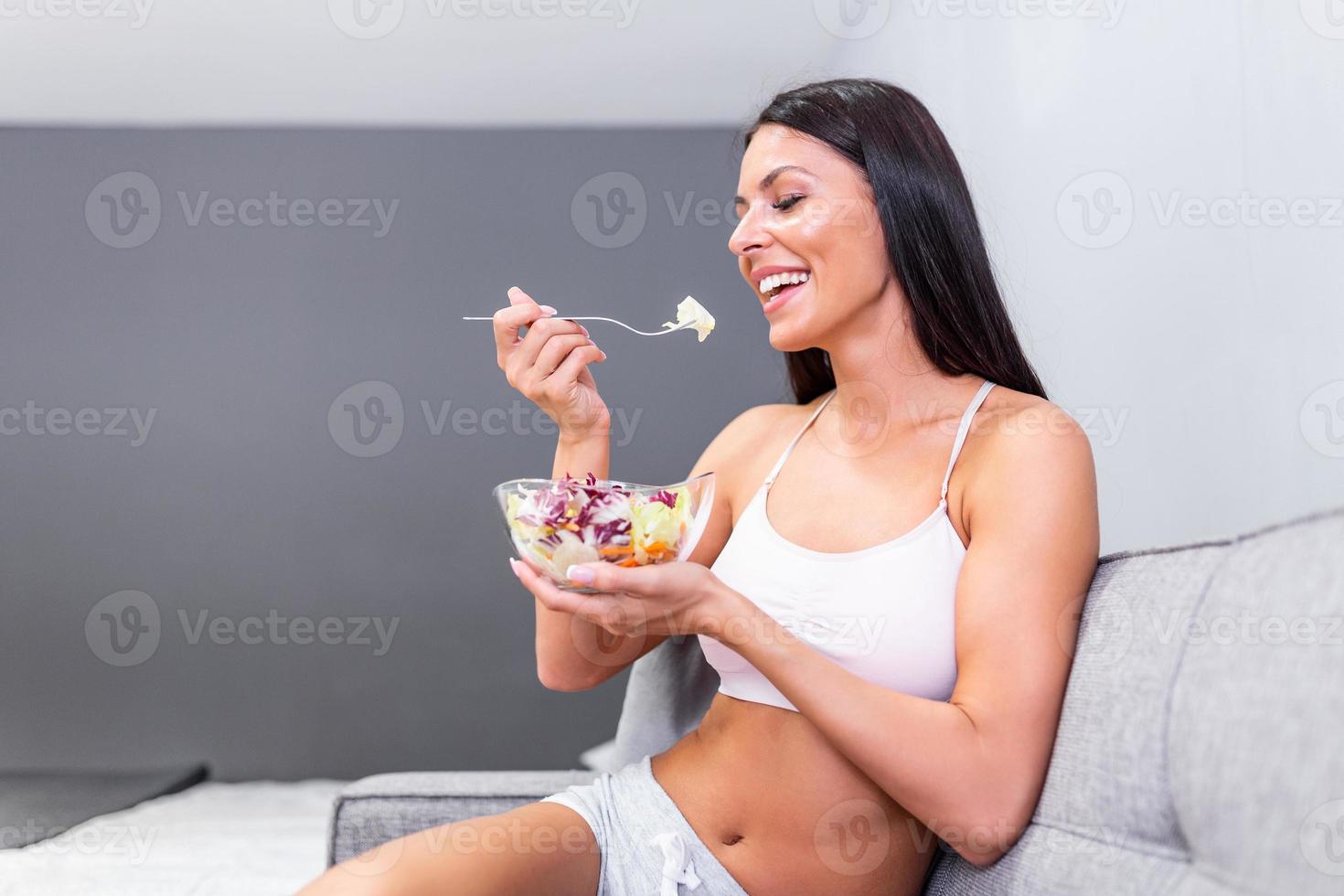 mulher jovem e bonita comendo salada de legumes. dieta saudável. bela mulher sorridente comendo salada vegetariana orgânica fresca. alimentação saudável, conceito de comida e estilo de vida. saúde, beleza, conceito de dieta. foto