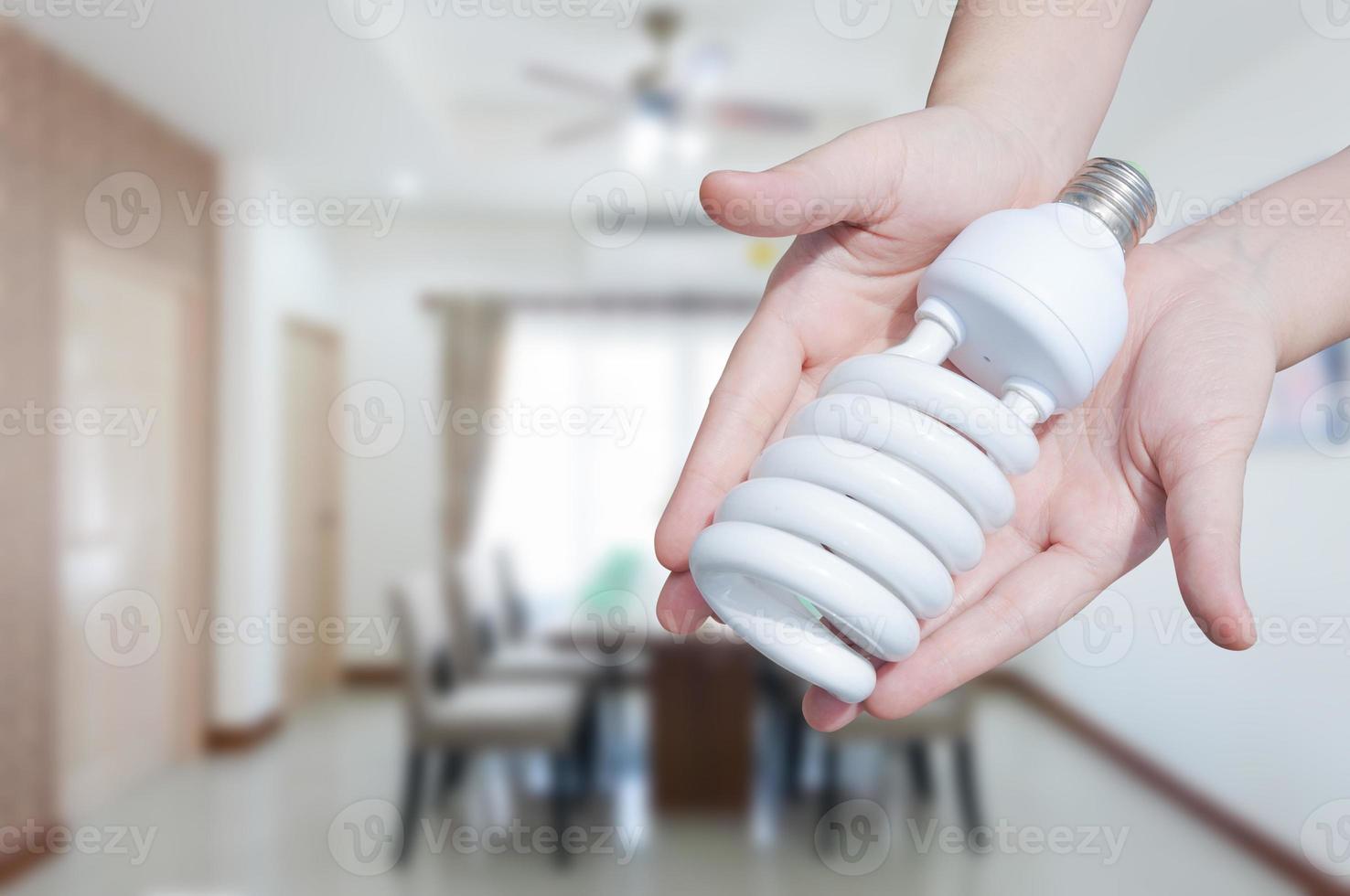 energia salvando conceito, mulher mão segurando luz lâmpada em quarto casa plano de fundo, ideias luz lâmpada dentro a mão foto