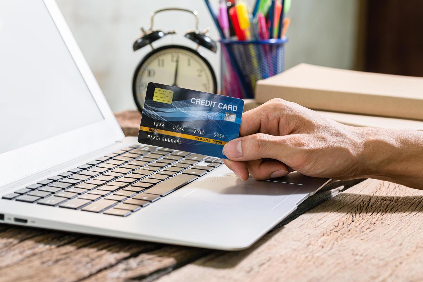 pessoa que usa um cartão de crédito para fazer compras online através do computador foto