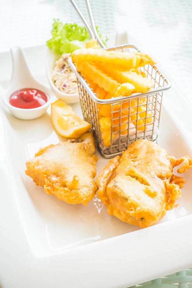 peixe e batata frita em um prato branco foto