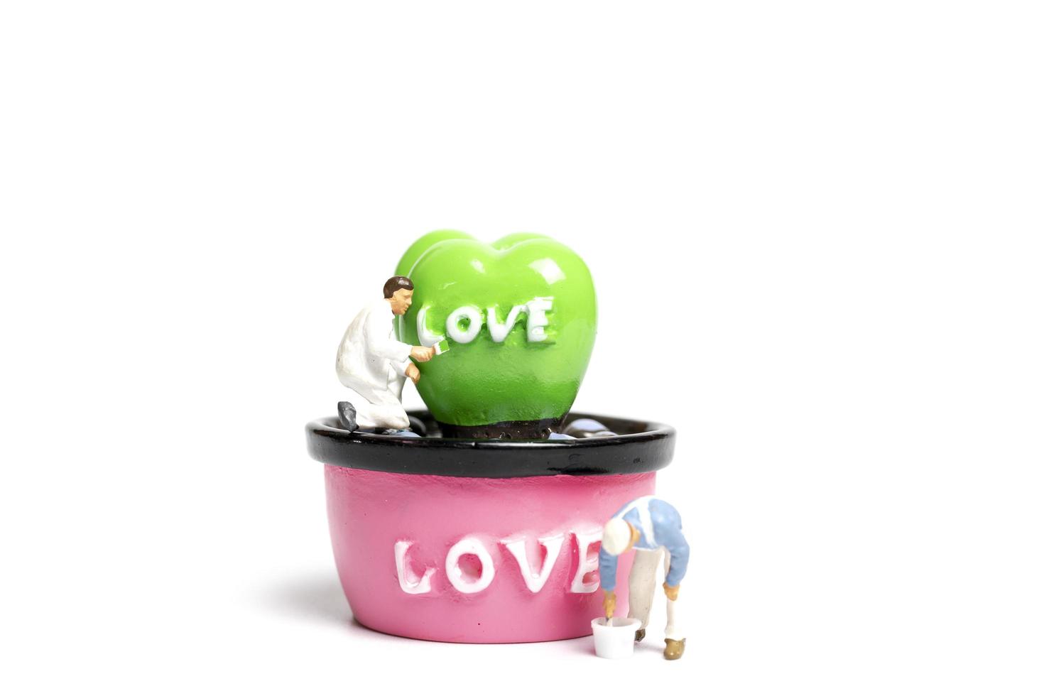 pintores em miniatura colorindo plantas em uma cápsula com a palavra amor, conceito de dia dos namorados foto