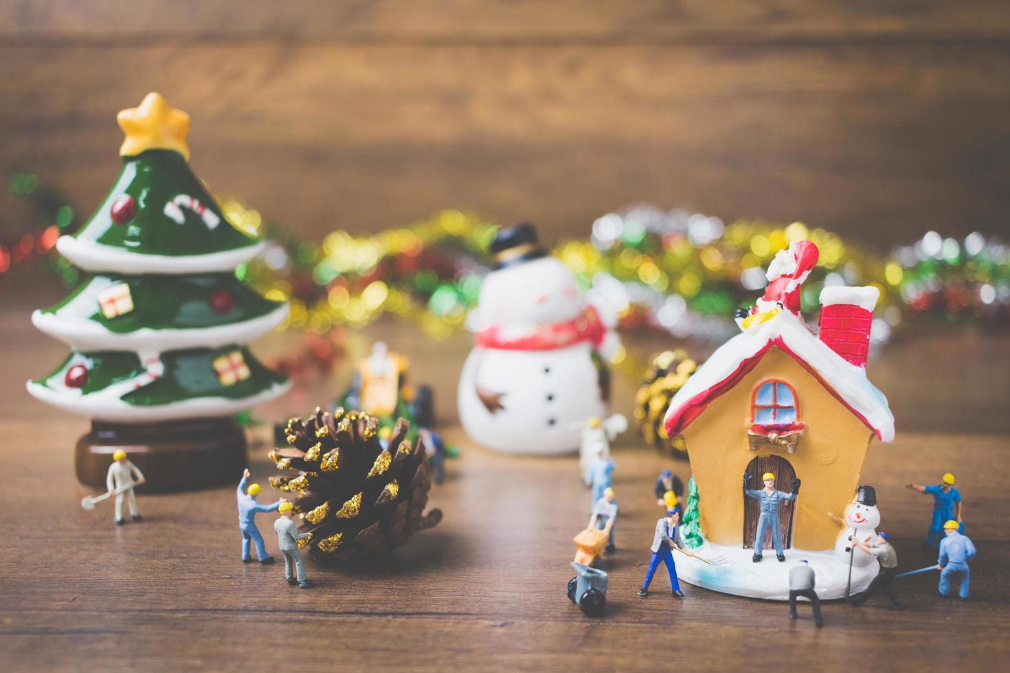 pessoas em miniatura criando decorações de Natal em um fundo de madeira foto