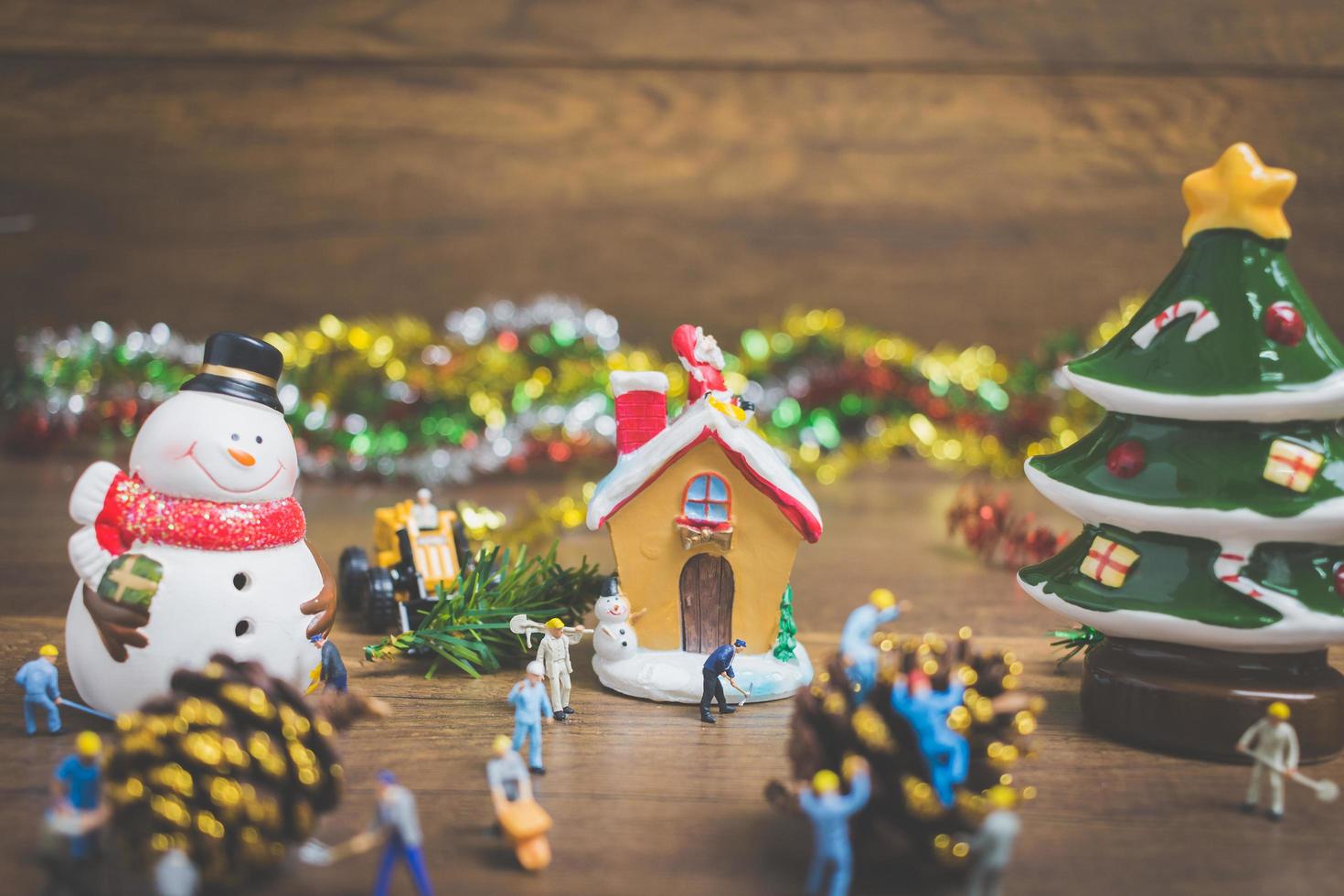 pessoas em miniatura criando decorações de Natal em um fundo de madeira foto