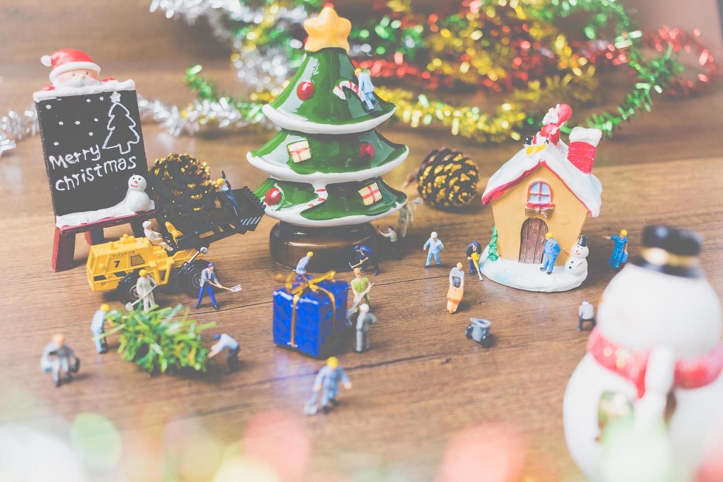 pessoas em miniatura criando decorações de Natal em um fundo de madeira foto