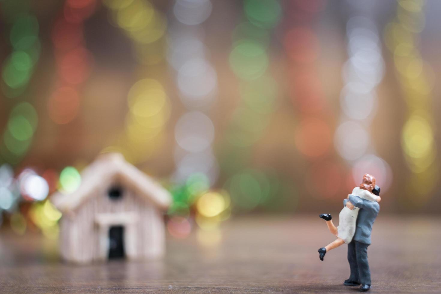 casal em miniatura se abraçando em um chão de madeira com um fundo colorido bokeh, conceito de família de sucesso foto