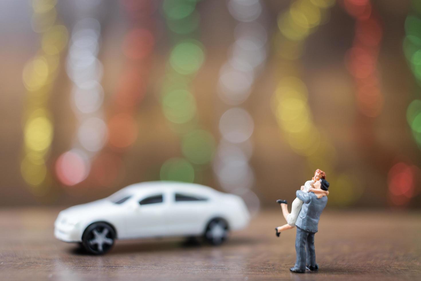 casal em miniatura se abraçando em um chão de madeira com um fundo colorido bokeh, conceito de família de sucesso foto