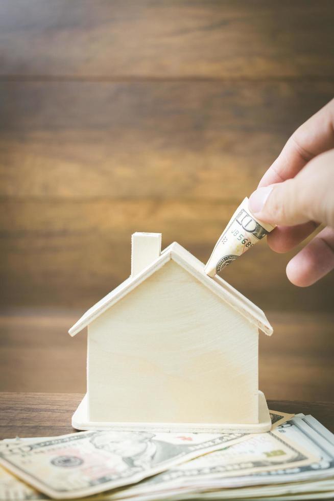 modelo de dinheiro e casa em um fundo de madeira, finanças e conceito bancário foto