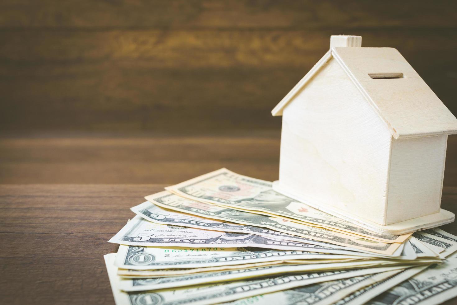 modelo de dinheiro e casa em um fundo de madeira, finanças e conceito bancário foto