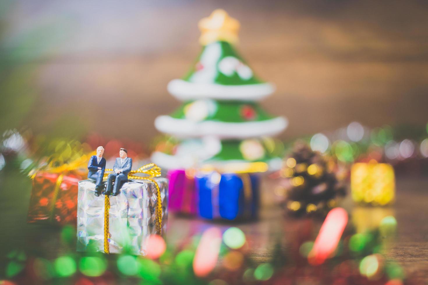 pessoas em miniatura em uma caixa de presente com decoração de celebração de Natal ao fundo foto