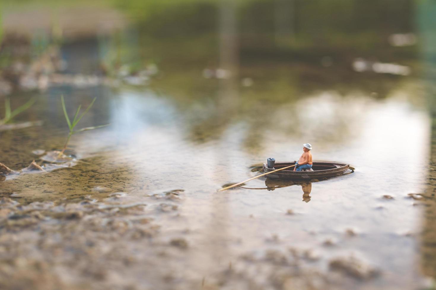 pescador em miniatura pescando em um barco foto