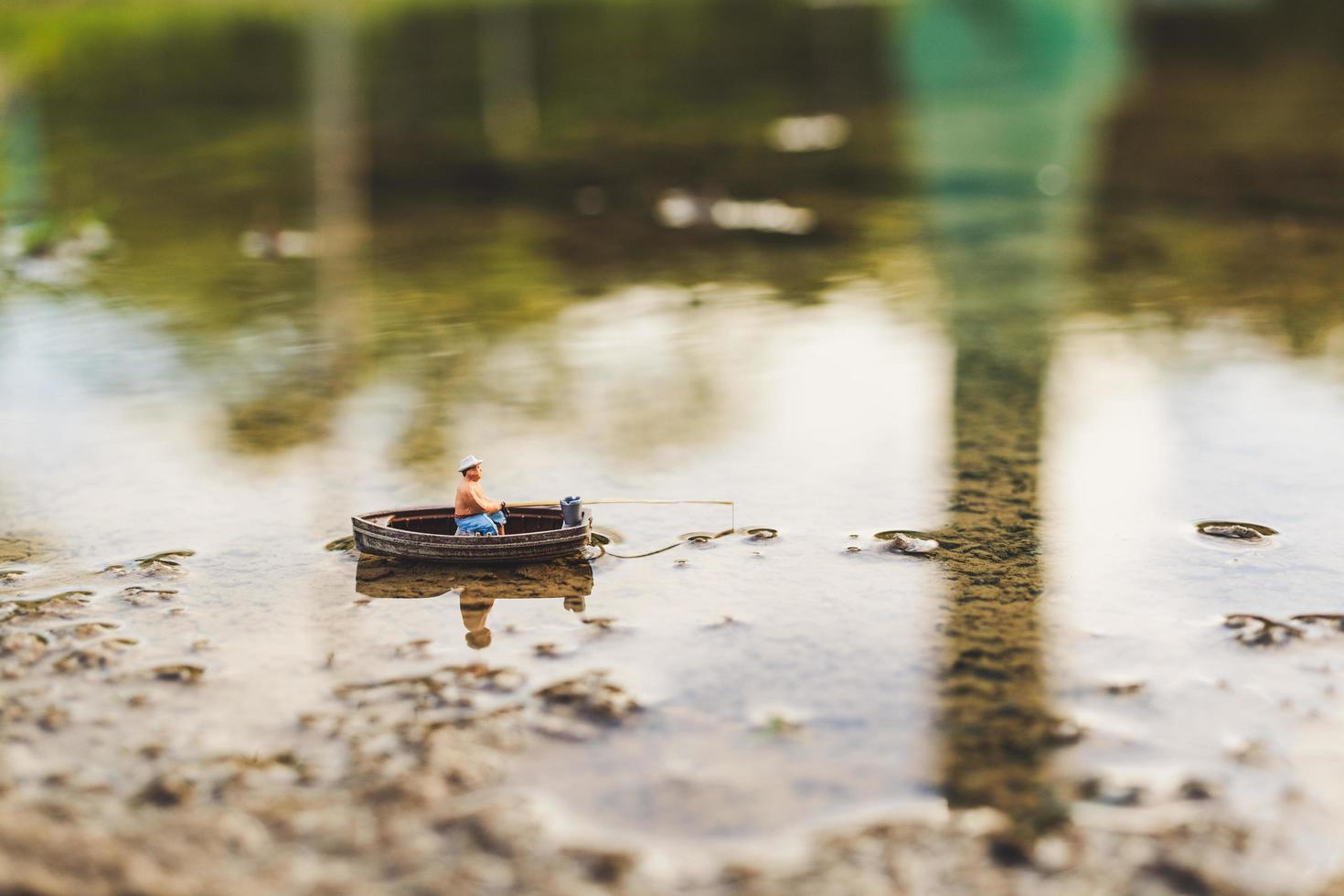 pescador em miniatura pescando em um barco foto