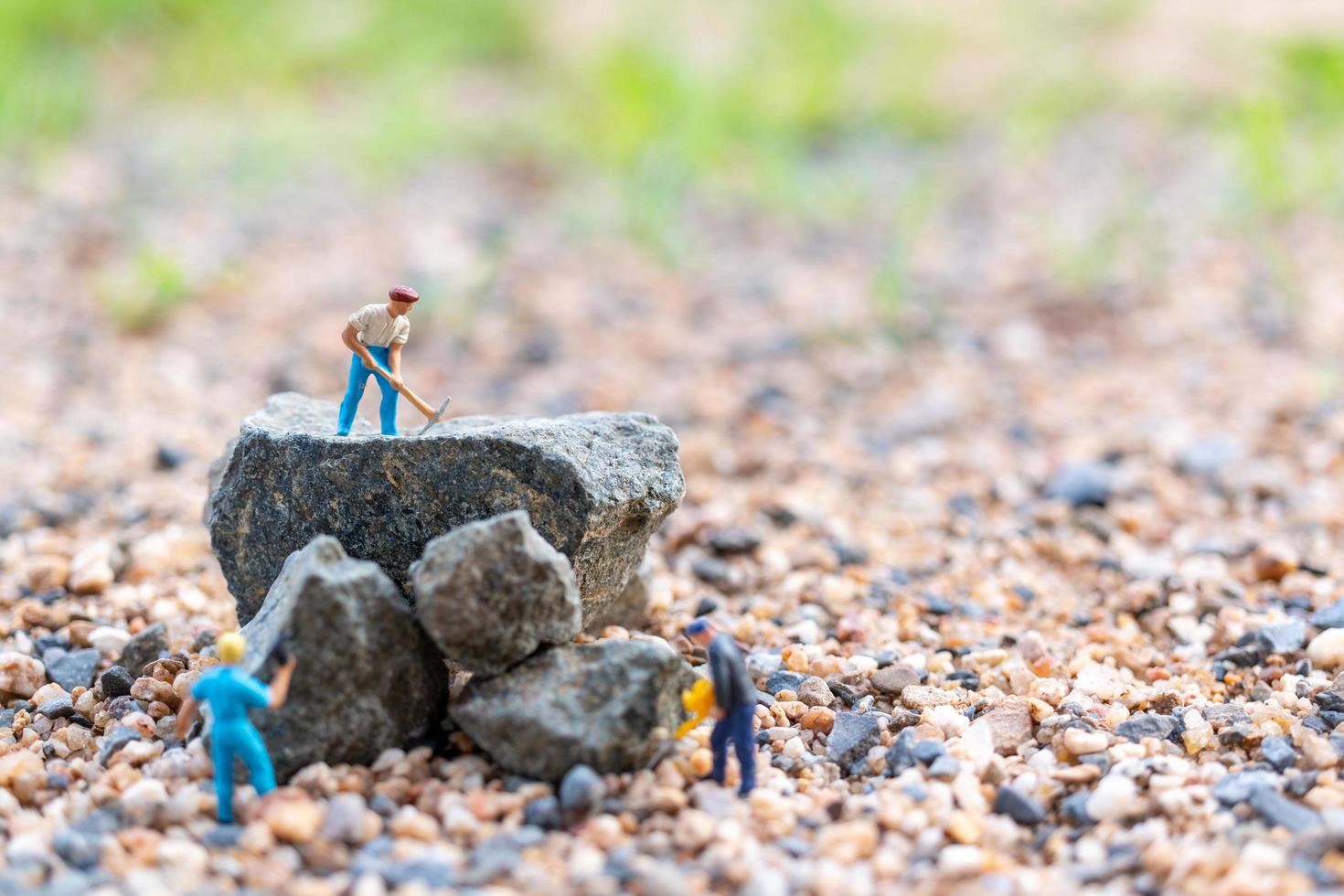 trabalhadores em miniatura sobre uma rocha, conceito de trabalho em equipe foto