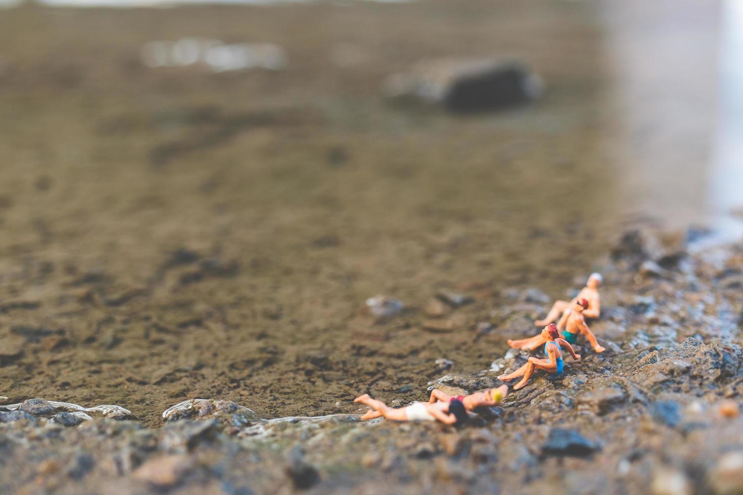 pessoas em miniatura usando maiôs relaxantes na praia, conceito de verão foto