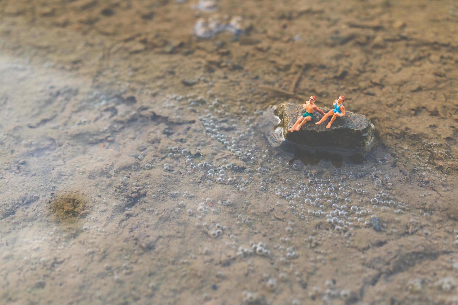 pessoas em miniatura usando maiôs relaxantes na praia, conceito de verão foto