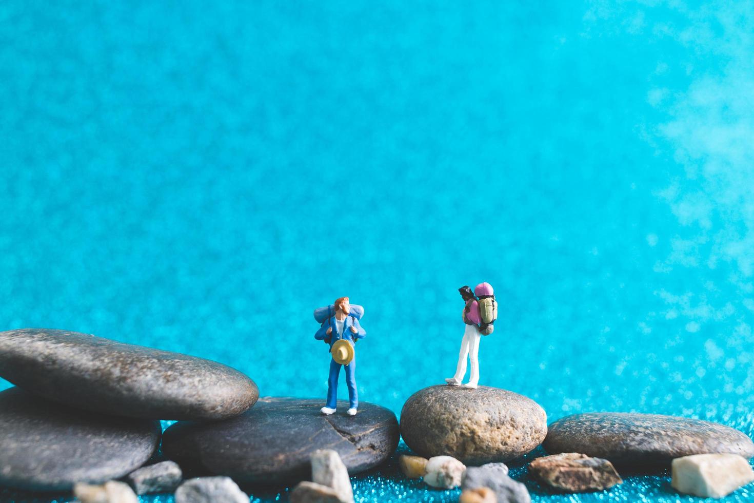 mochileiros em miniatura, turistas em um fundo azul brilhante foto