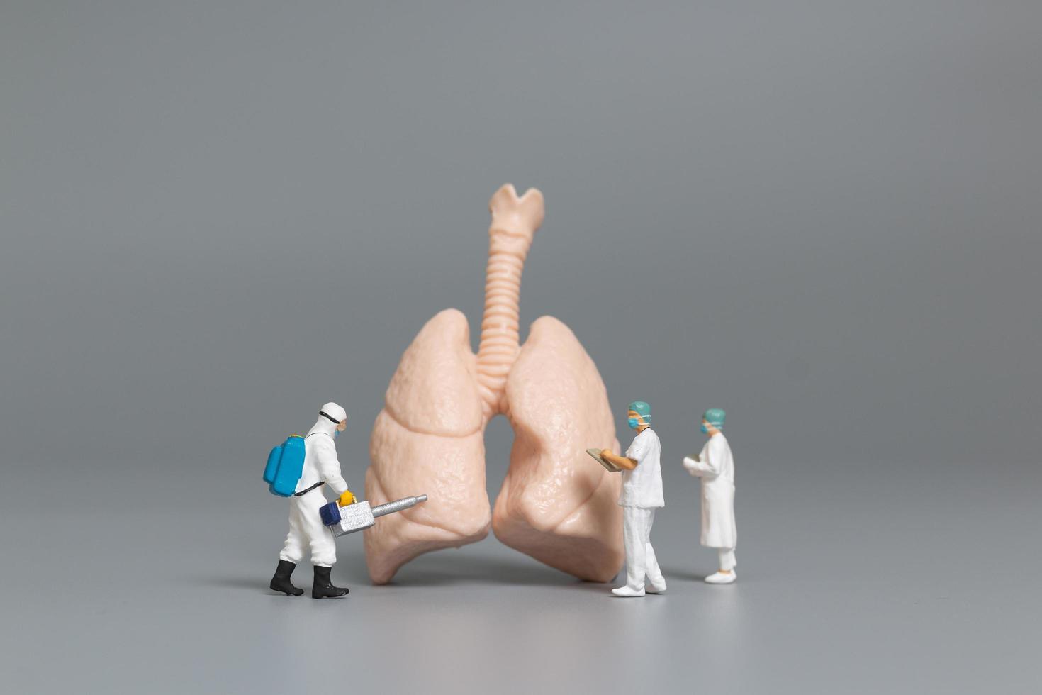 médicos e enfermeiras em miniatura observando e discutindo o conceito de pulmão humano, vírus e bactérias infectadas foto