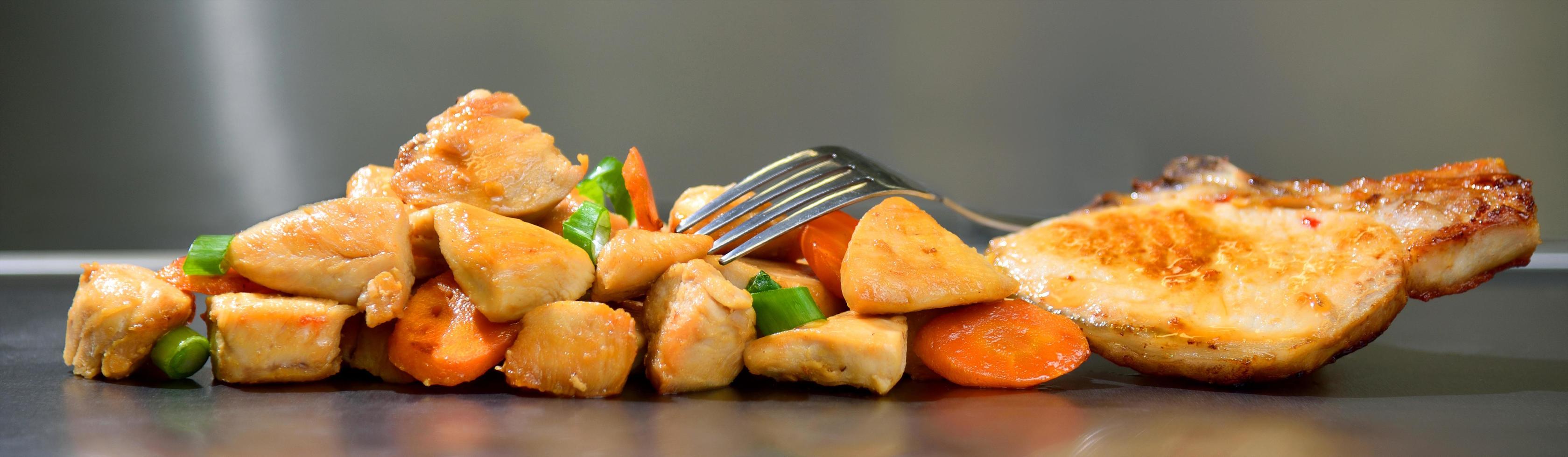 Fatias de frango assado temperado com cenoura e alho-poró em fundo de aço inoxidável foto