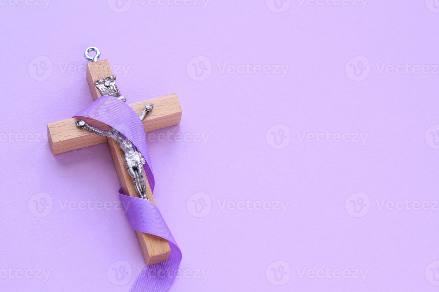 cristão religioso de madeira Cruz crucifixo com tolet fita em roxa fundo. católico religião símbolo. Boa sexta-feira, emprestado temporada, Palma Domingo, cinza quarta-feira e piedosos semana conceito foto