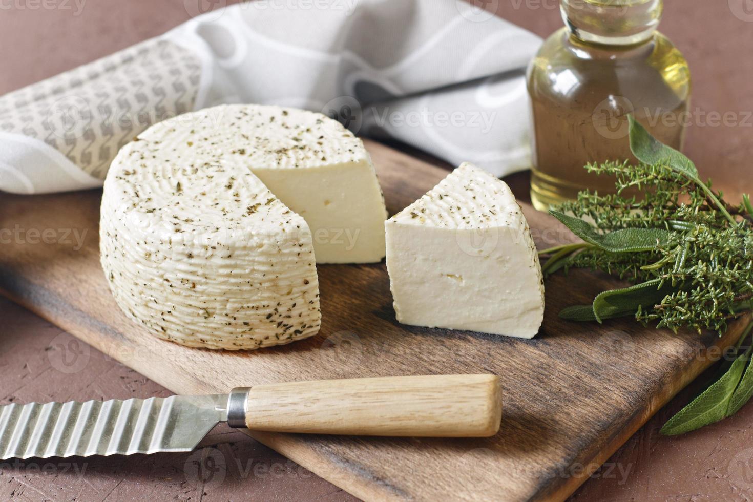 queijo branco em uma placa de madeira com azeite em um fundo marrom foto