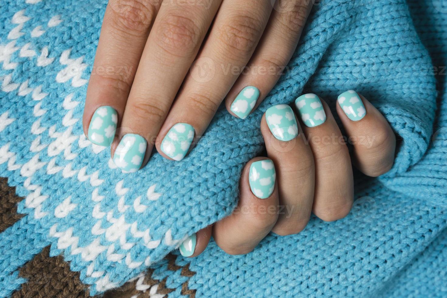 mulheres dedos e unhas com uma lindo colori manicure em a fundo do uma turquesa lã suéter foto