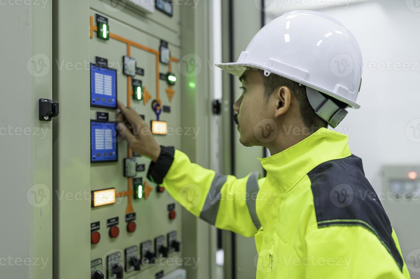 homem engenheiro elétrico verificando a tensão no gabinete de distribuição de energia na sala de controle, manutenção preventiva anualmente, eletricista tailandês trabalhando na empresa foto